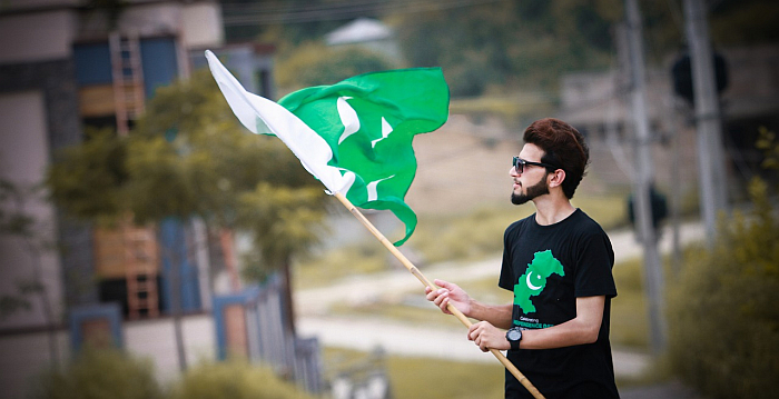 Chłopak w koszulce z flagą Pakistanu wymachuje flagą Pakistanu